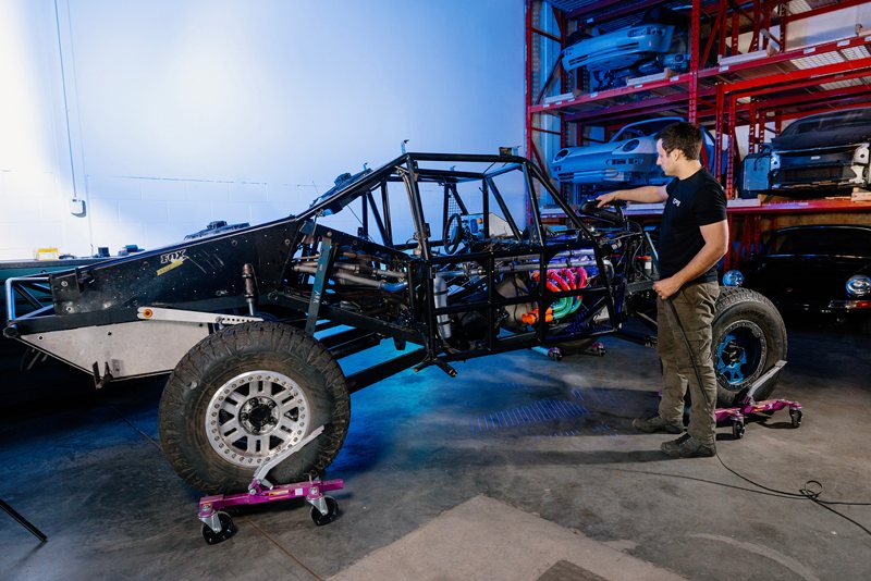 An EP9 Autosport technician scanning the race car chassis with a Creaform HandySCAN 3D|PRO Series in the workshop, capturing the geometry of the complete vehicle.
