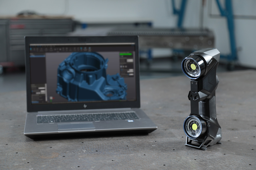 Portable 3D scanner and laptop showing the scan of an automotive die casting part shown in a 3D software