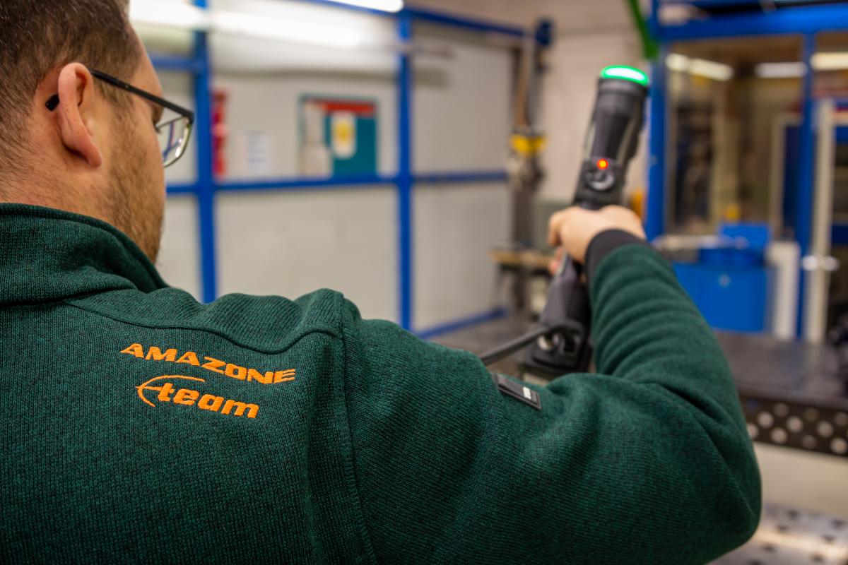 An engineer wearing an Amazone sweater is scanning a part with Creaform metrology-grade 3D scanners.